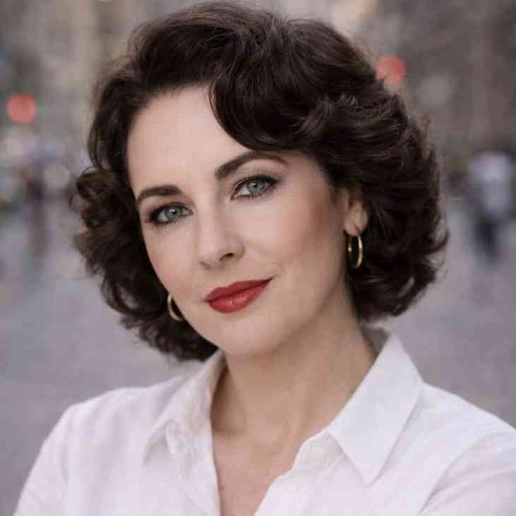 GraceVoice Woman with short dark curly hair and a serious expression